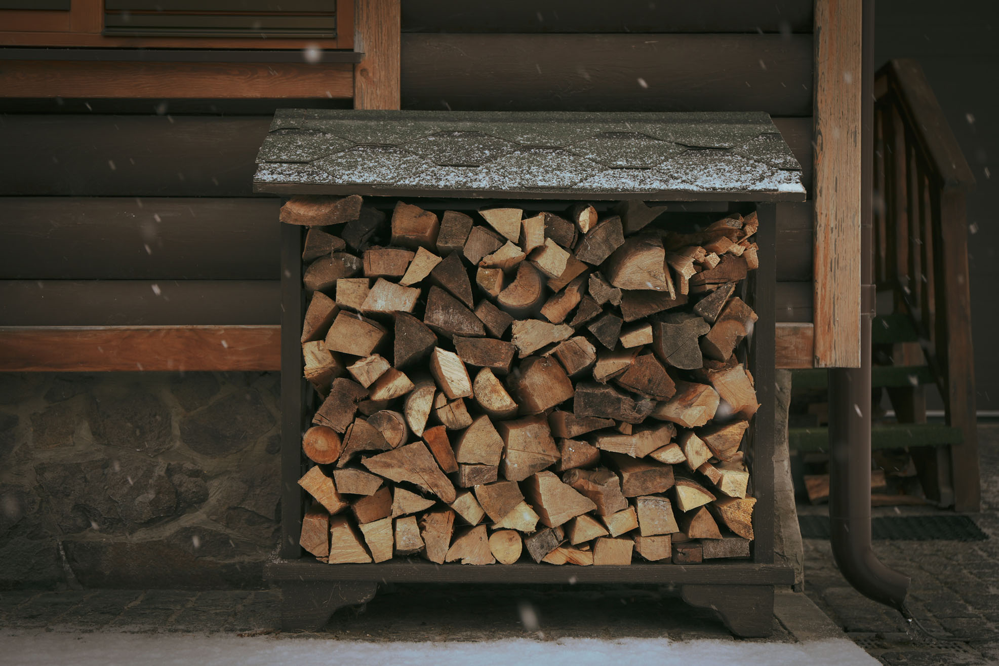 Firewood near a wooden house on a snowy day